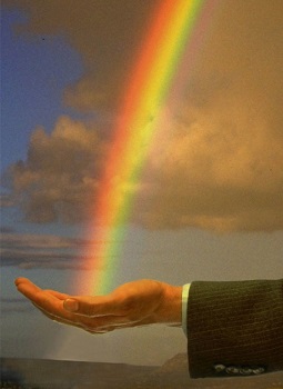 un arc en ciel se pose sur une main