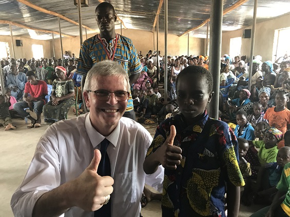 Le Pasteur Michel Genton et un petit garçon avec le pouce levé dans une église à Fada (Burkina-Faso)